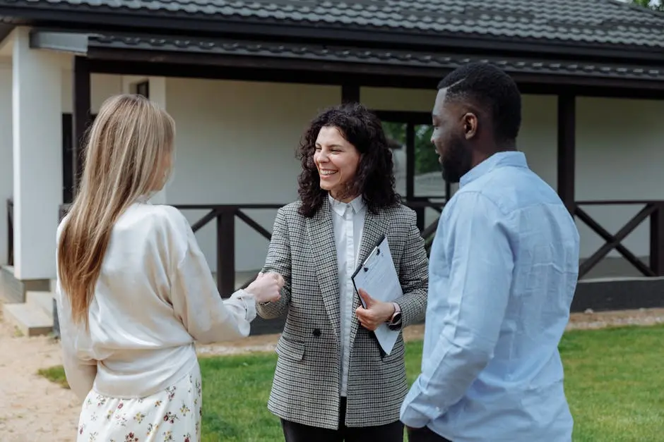 A real estate agent shakes hands with a couple outside a modern house, symbolizing a successful property deal.