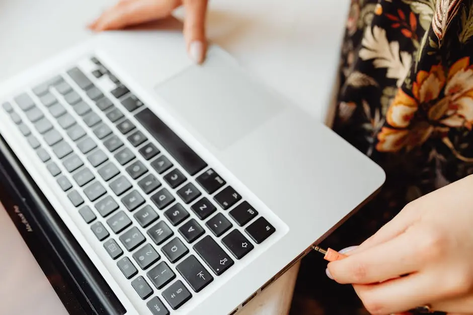 Close-up of a person inserting an audio jack into a laptop. Technology and connectivity concept.