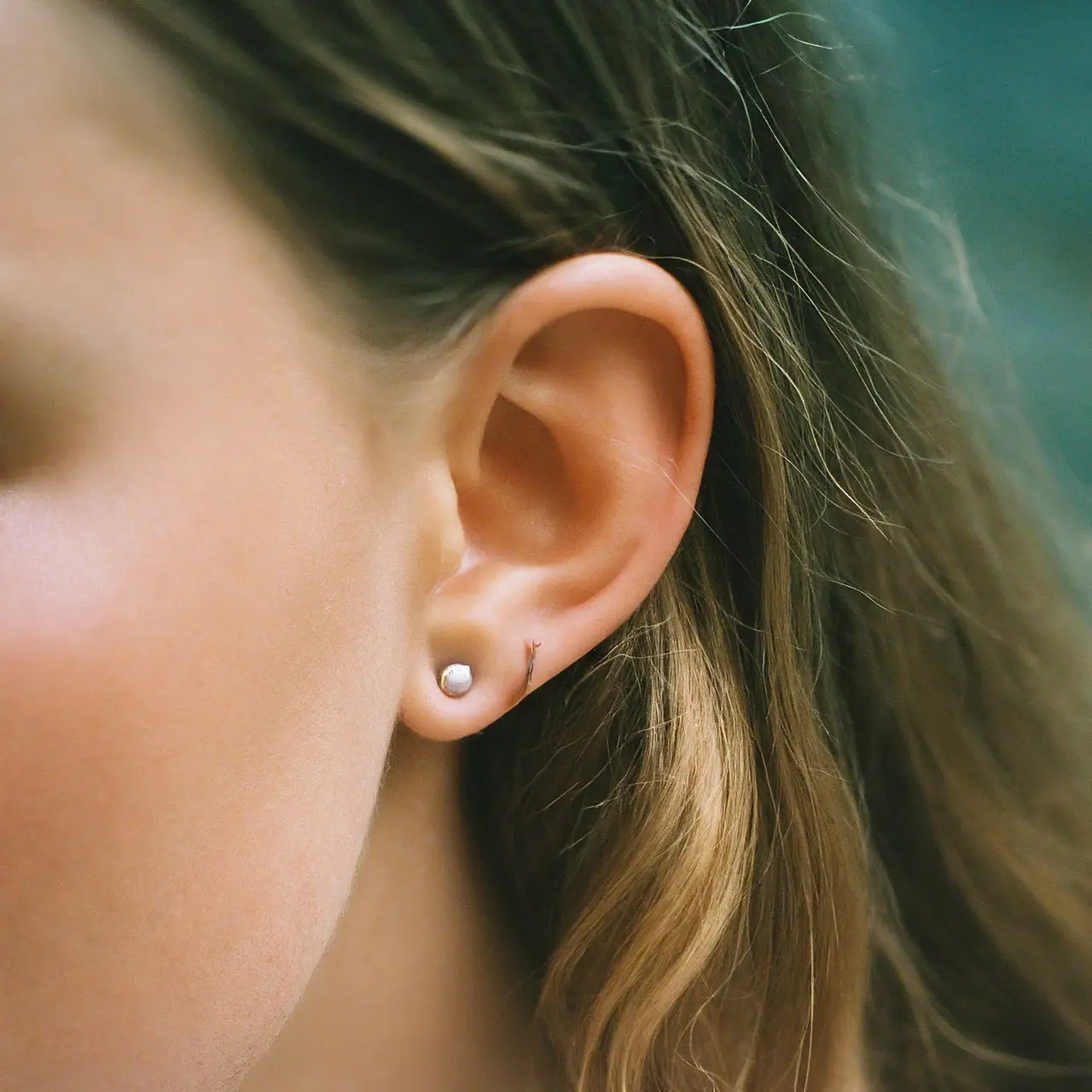 A simple ear with a small, freshly pierced stud earring. 35mm stock photo