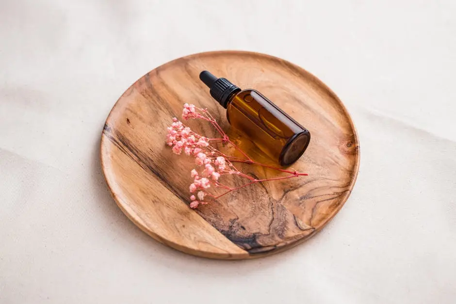 Photo of a Brown Bottle and Pink Flowers on a Wooden Surface