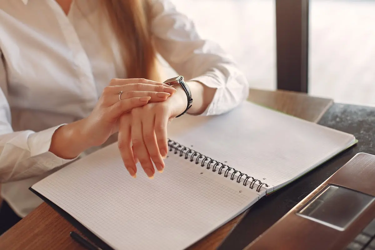 Faceless crop female entrepreneur checking time  while working with papers