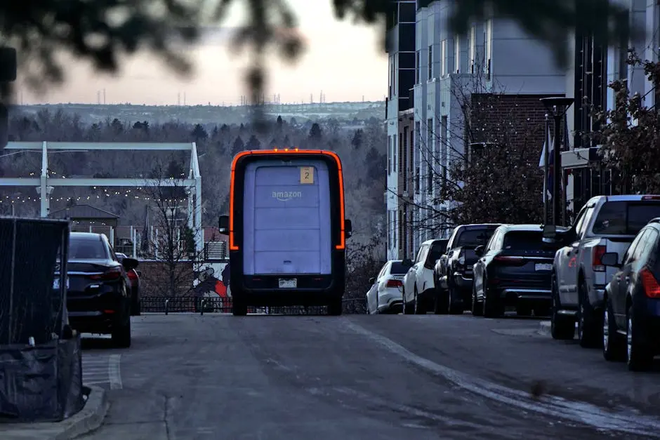 A truck is driving down a street with cars parked on the side