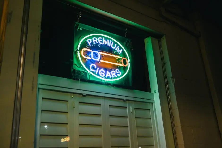 Illuminated neon sign for premium cigars outside a building at night.