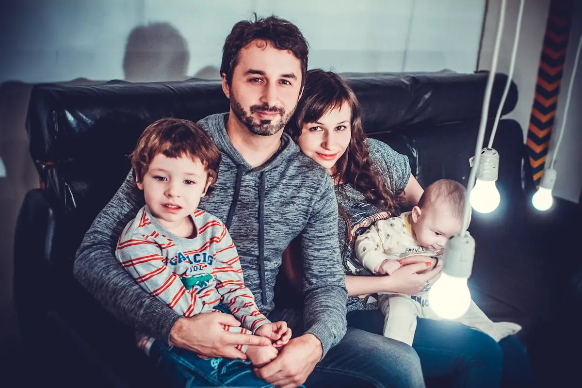 Man and Woman Carrying Babies While Sitting on Chair