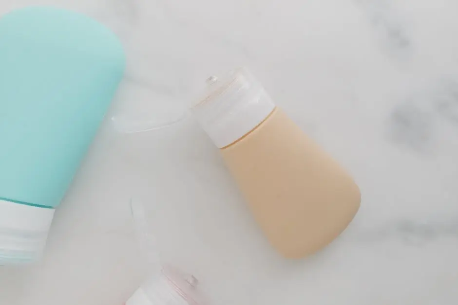 Soft-colored squeezable travel bottles with flip-top caps on a marble surface, ideal for packaging needs.