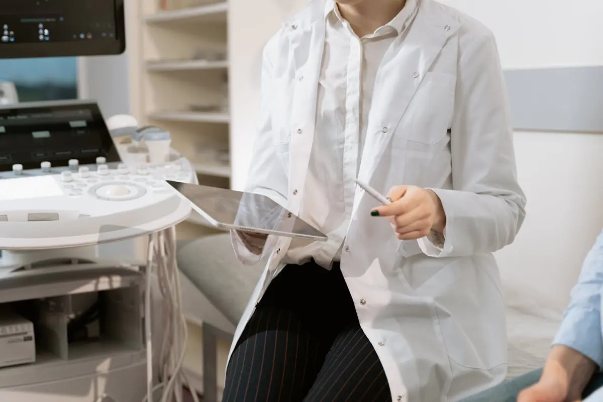 Doctor holding a tablet in a modern medical office during a patient consultation.