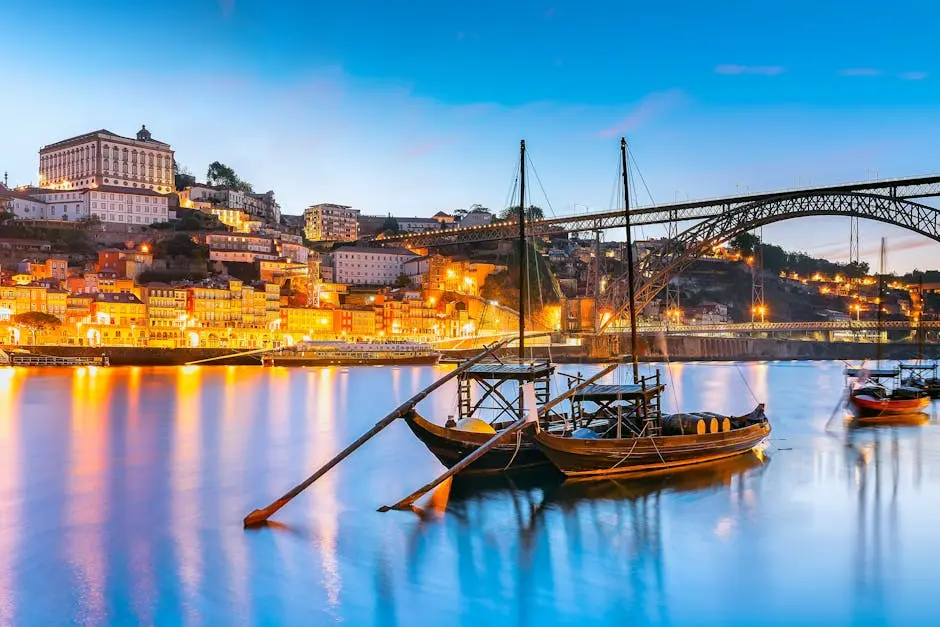 Scenic view of Rabelo boats and Porto cityscape at twilight on the Douro River.