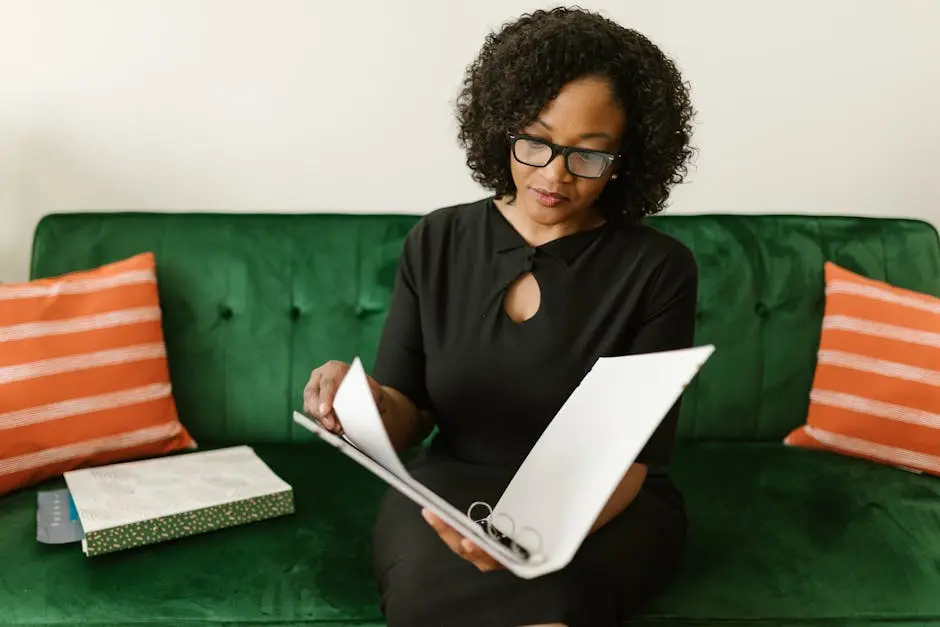 Businesswoman in an office setting reviewing papers on a green sofa. Perfect for work from home concepts.