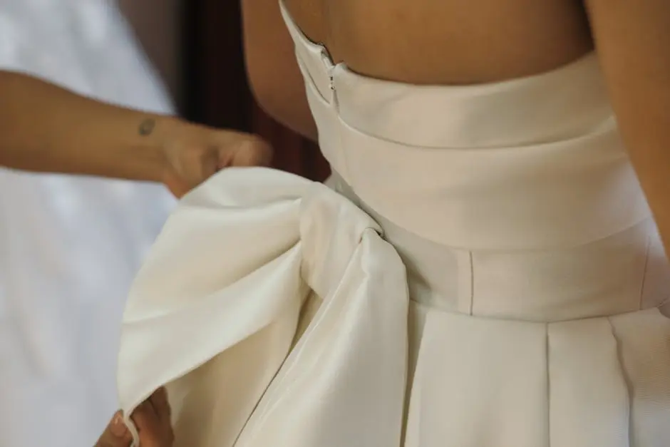 Close-up of Bridesmaid Fixing the Brides Dress