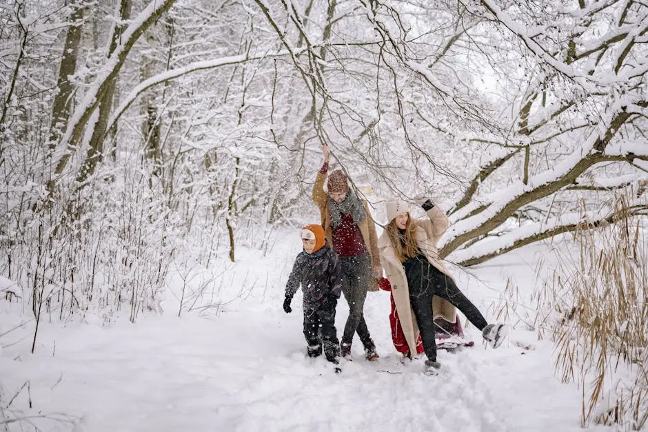 A Family in Winter Clothes Walking on a Snow-Covered Ground near the Tree Branches