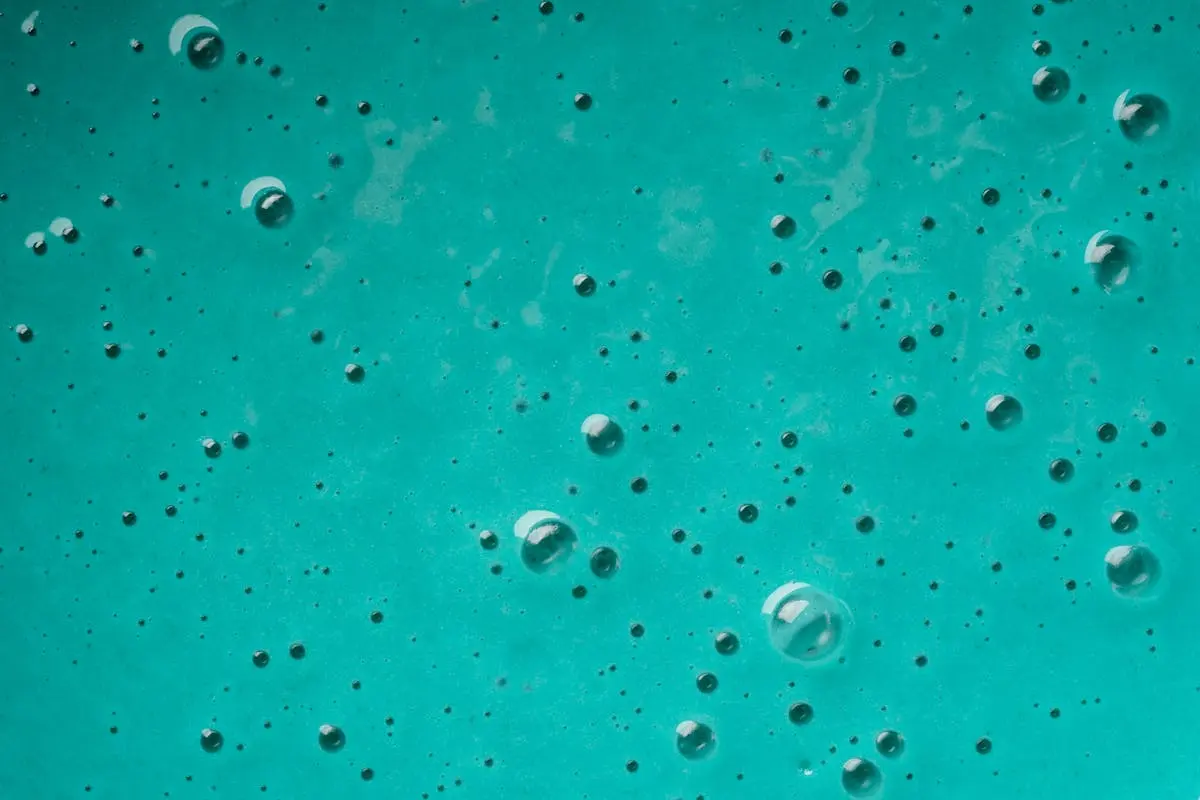 Abstract close-up of turquoise liquid with bubbles, showcasing texture and pattern.