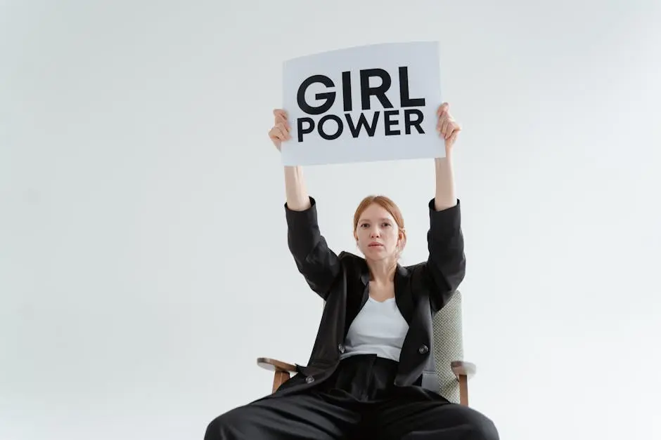 Woman in Black Blazer and Pants Holding a Girl Power Postcard