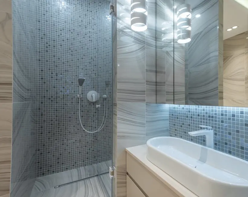 Stylish modern bathroom interior design with shower enclosure and oval sink under creative luminous lamp