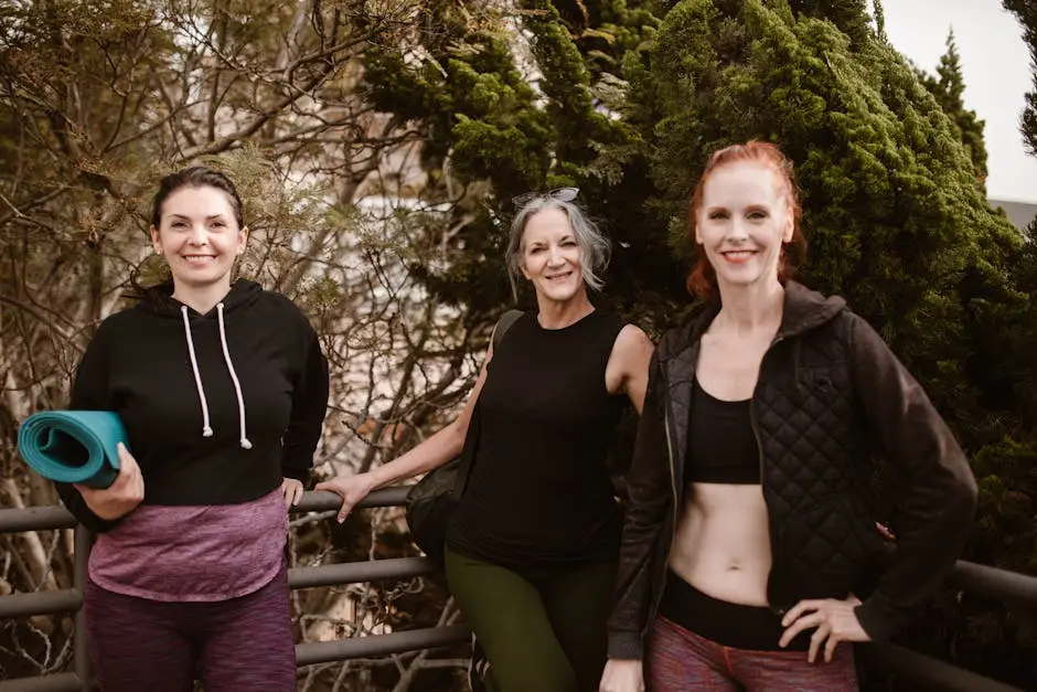 Three women smiling at the camera while posing outdoors in activewear, promoting healthy lifestyle.