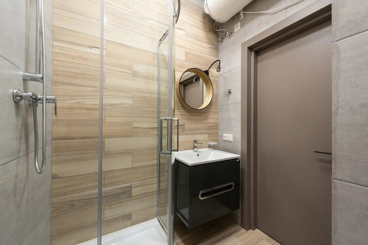 Interior of modern bathroom with ceramic sink and shower with glass walls designed in minimal style