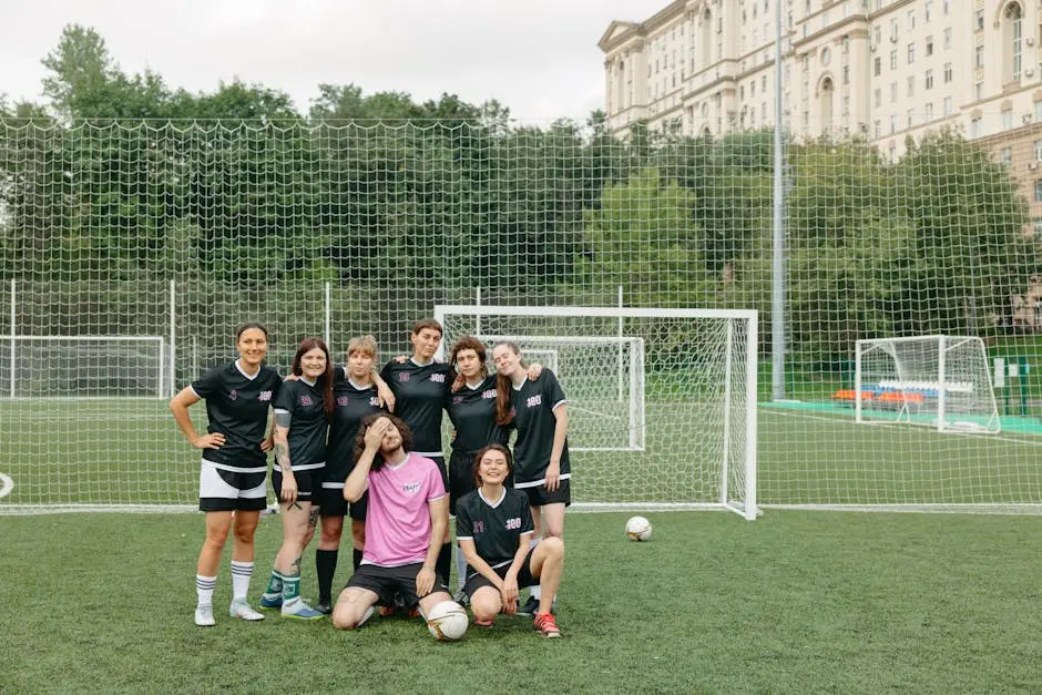 A group of women soccer players posing happily on a field, showcasing teamwork and diversity.