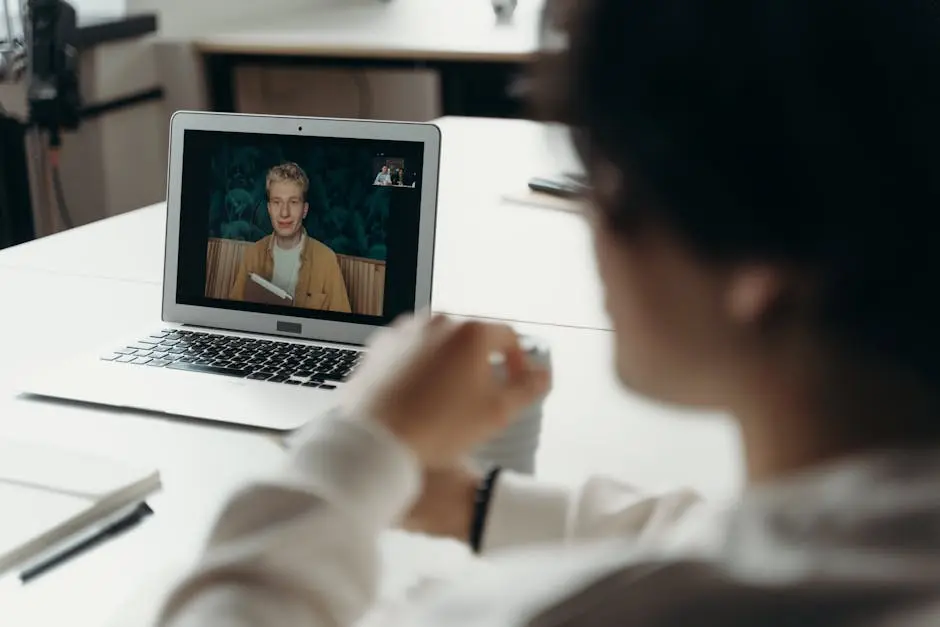 Two professionals having a virtual meeting via laptop in an office setting.