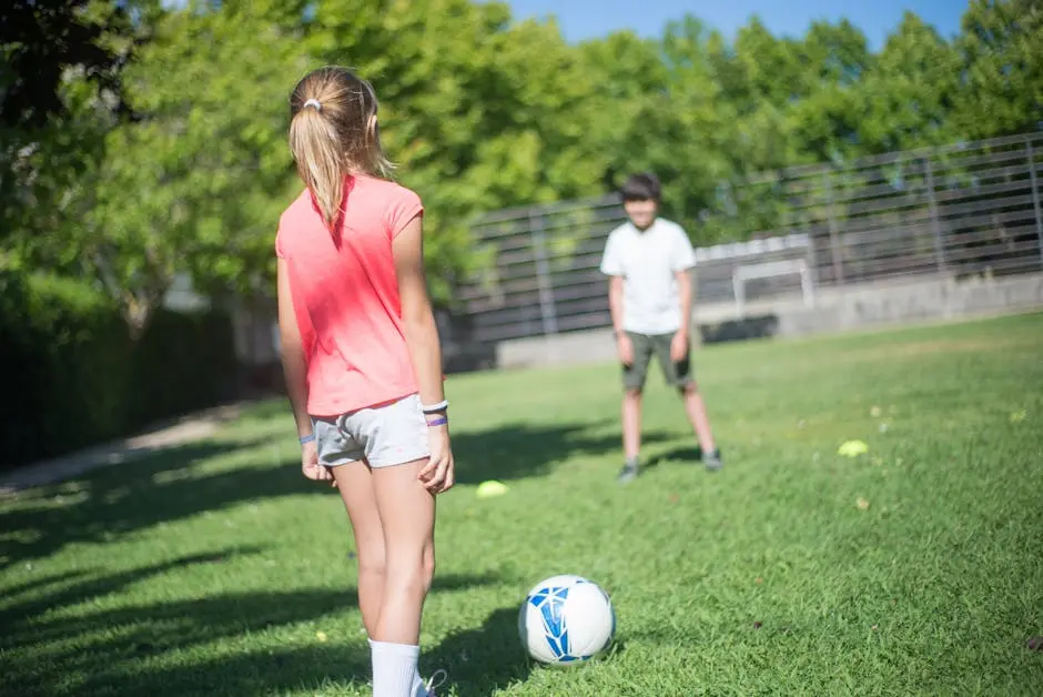 Kids having fun while playing soccer outdoors in a park on a sunny day.