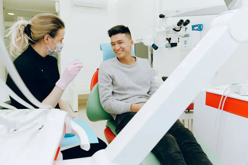 A dentist and patient smiling during a dental checkup, showcasing friendly healthcare interaction indoors.