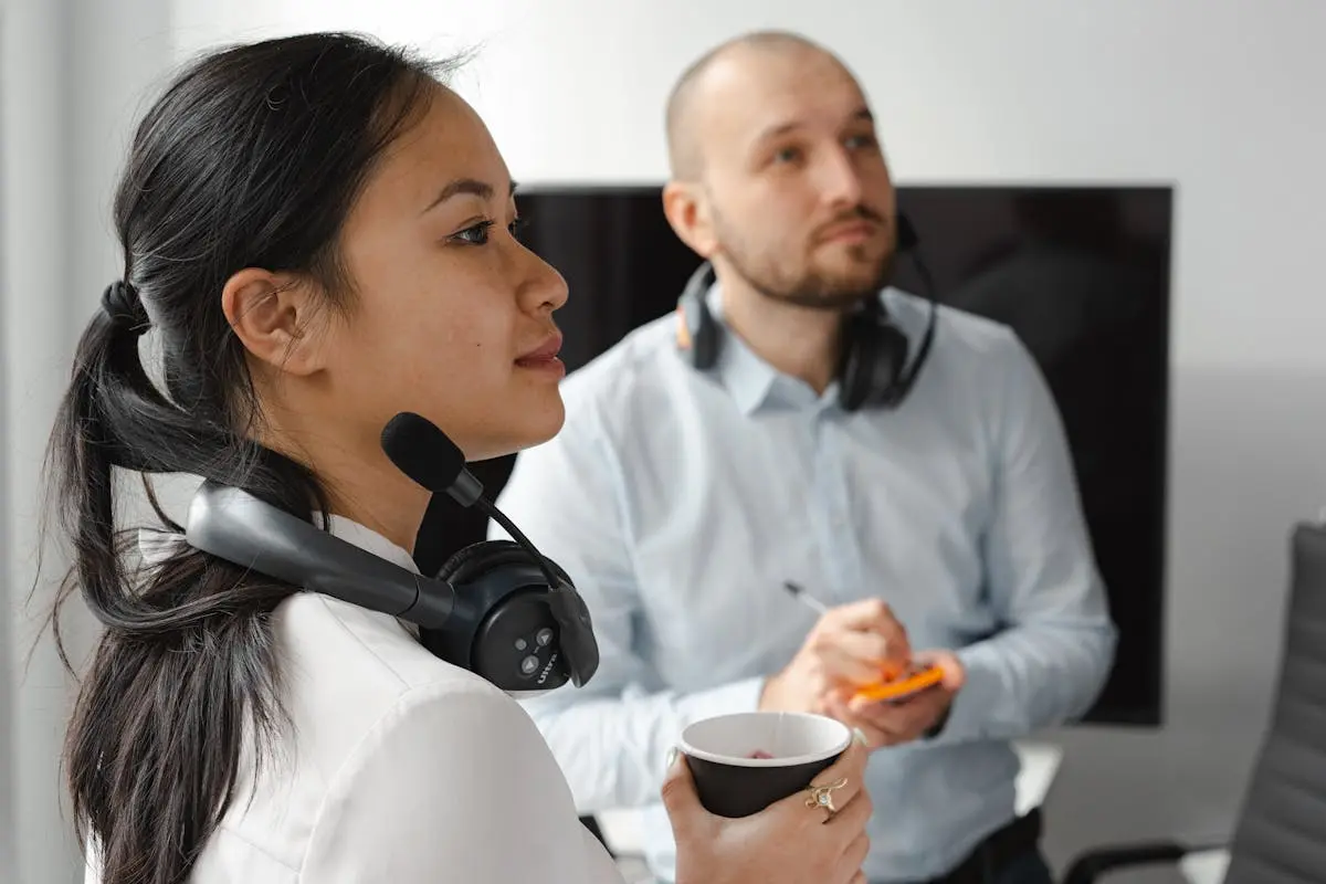 Two call center agents with headsets working in an office environment, focusing on customer support tasks.