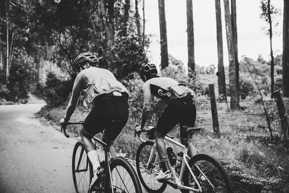 Two cyclists riding road bikes through a scenic forest trail, showcasing outdoor adventure.