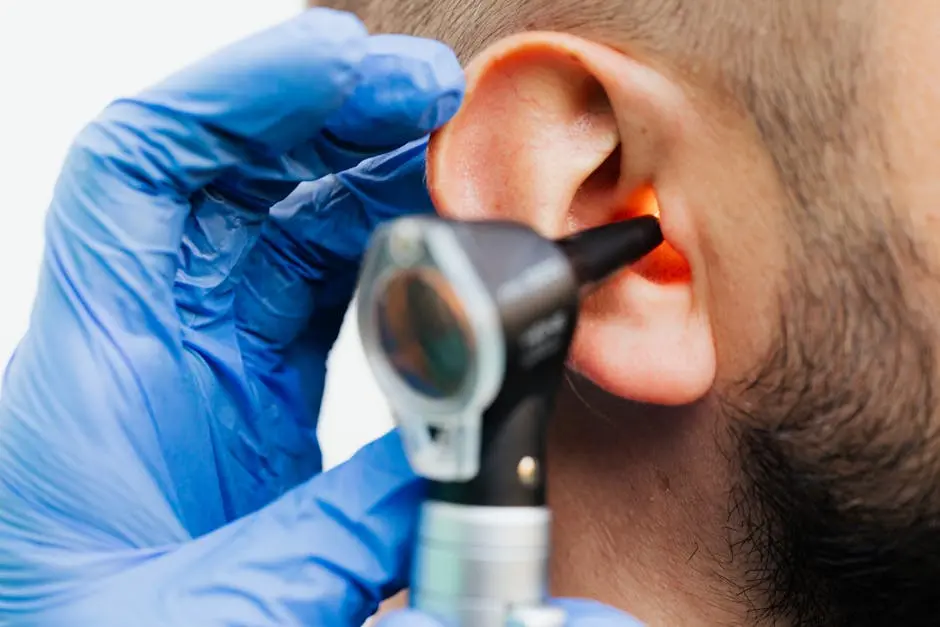 Close-up of a doctor using an otoscope to examine a patient’s ear in a clinical setting.