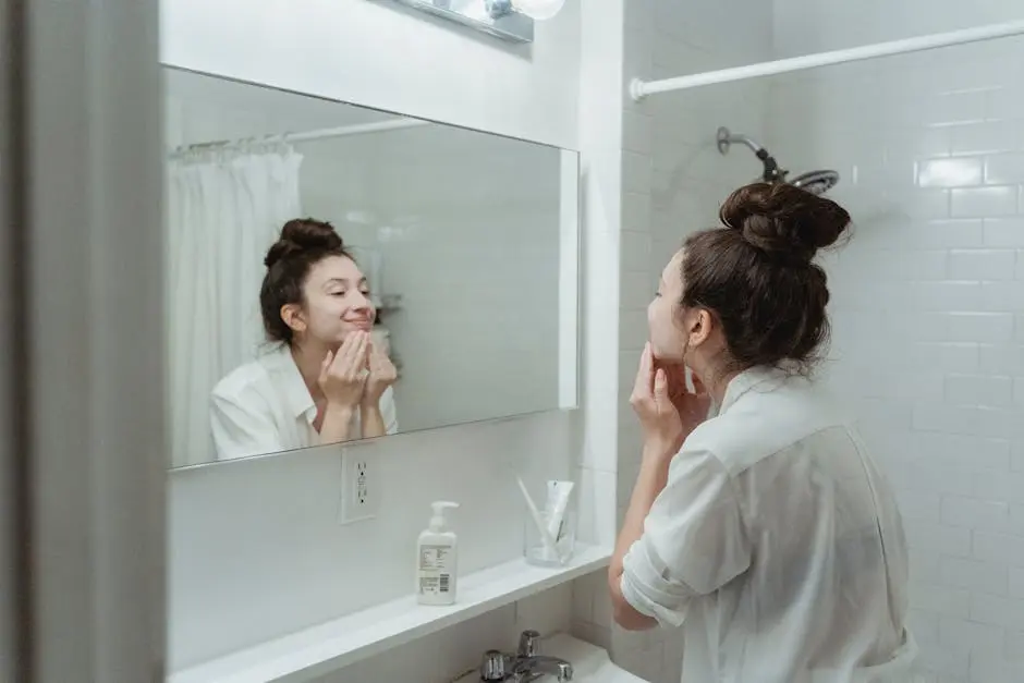 A woman applying skincare cream while looking in the bathroom mirror.