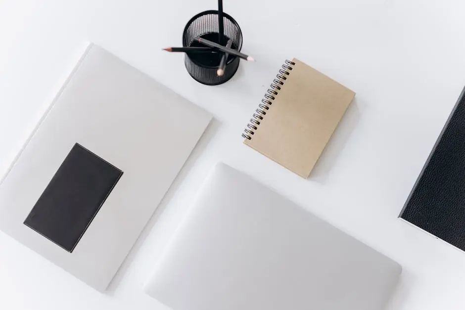 Netbook with planner and jotter placed near pencils on desk