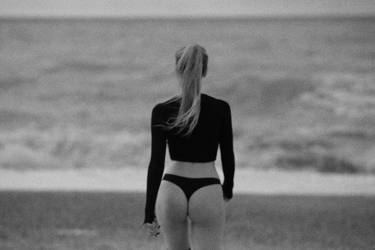 Grayscale Photo of a Woman Wearing Black Top at the Beach