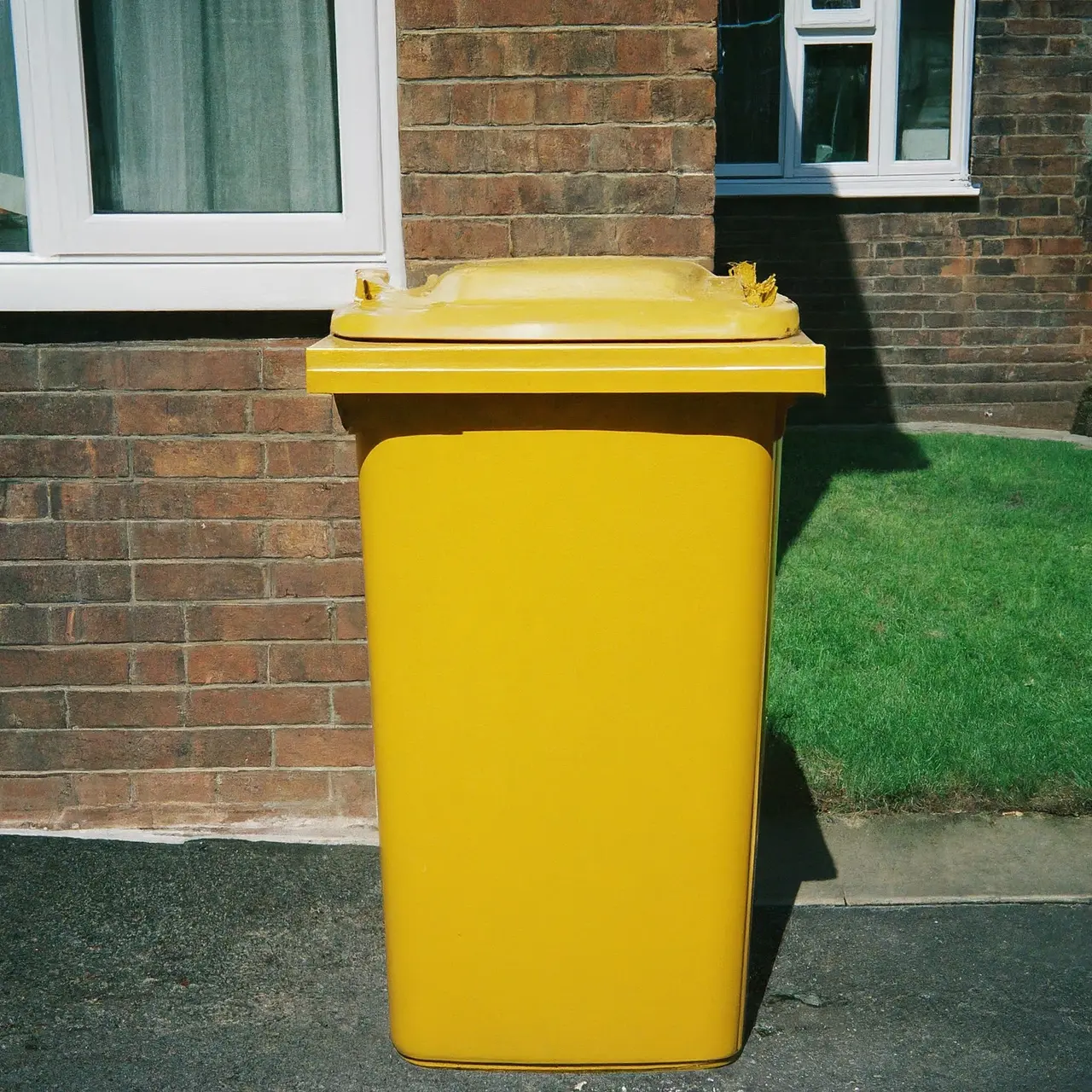 A large yellow disposal bin on a residential driveway. 35mm stock photo