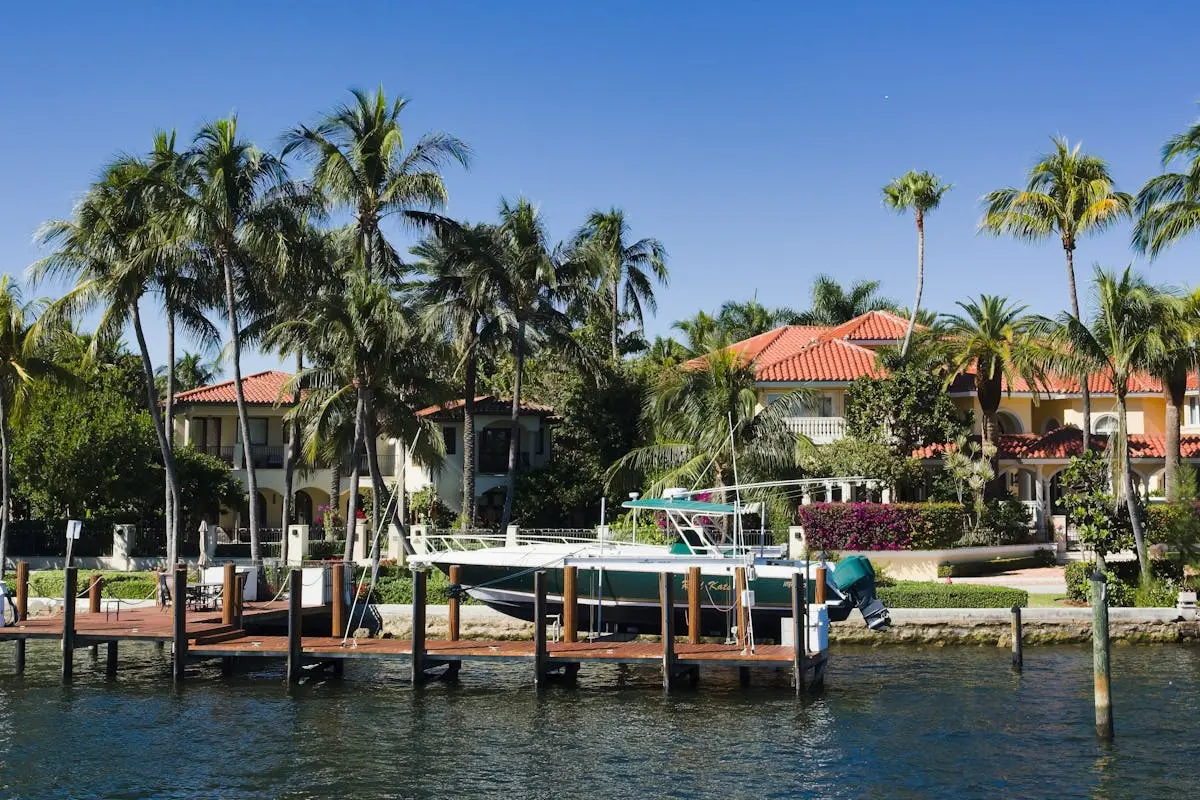 A Boat Moored near a Pier on a River with Houses and Palm Trees in the Background, Florida, USA