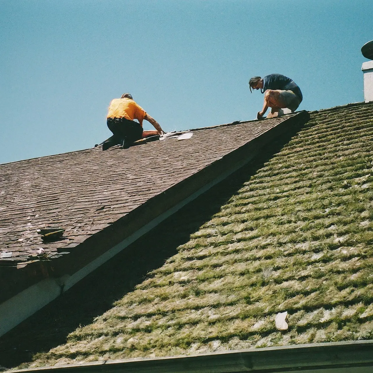 Roofers fixing leakage with tools on a sunny day. 35mm stock photo