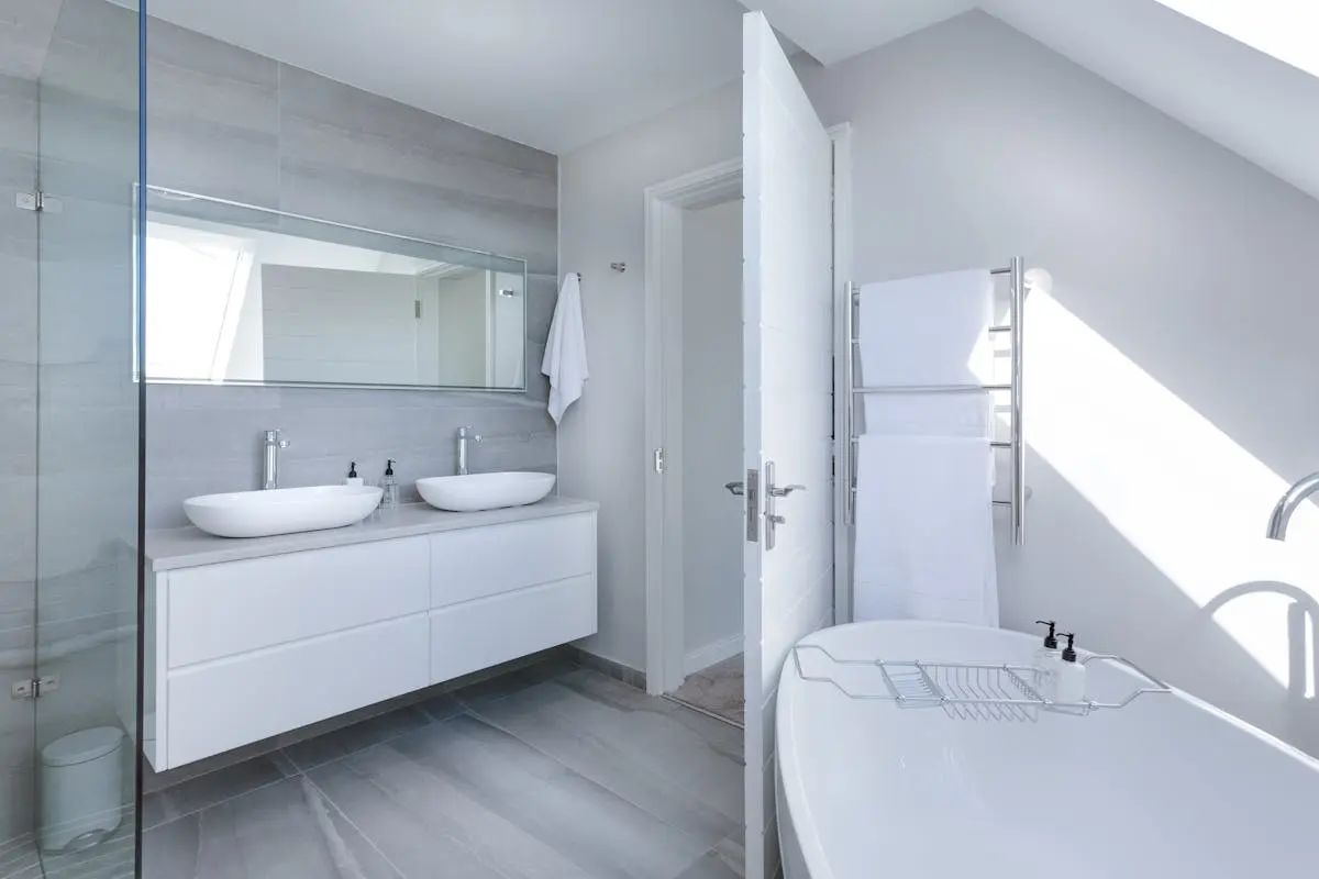 Sleek contemporary bathroom with bathtub and twin sinks, showcasing minimalist design and luxury.