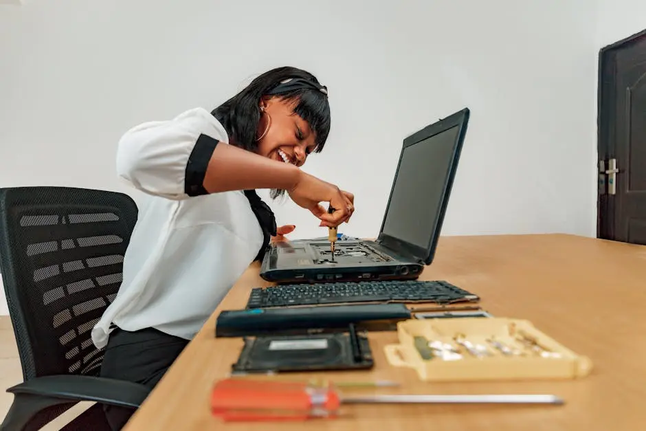 Woman repairing a laptop at a desk with tools, showcasing technology and skill.