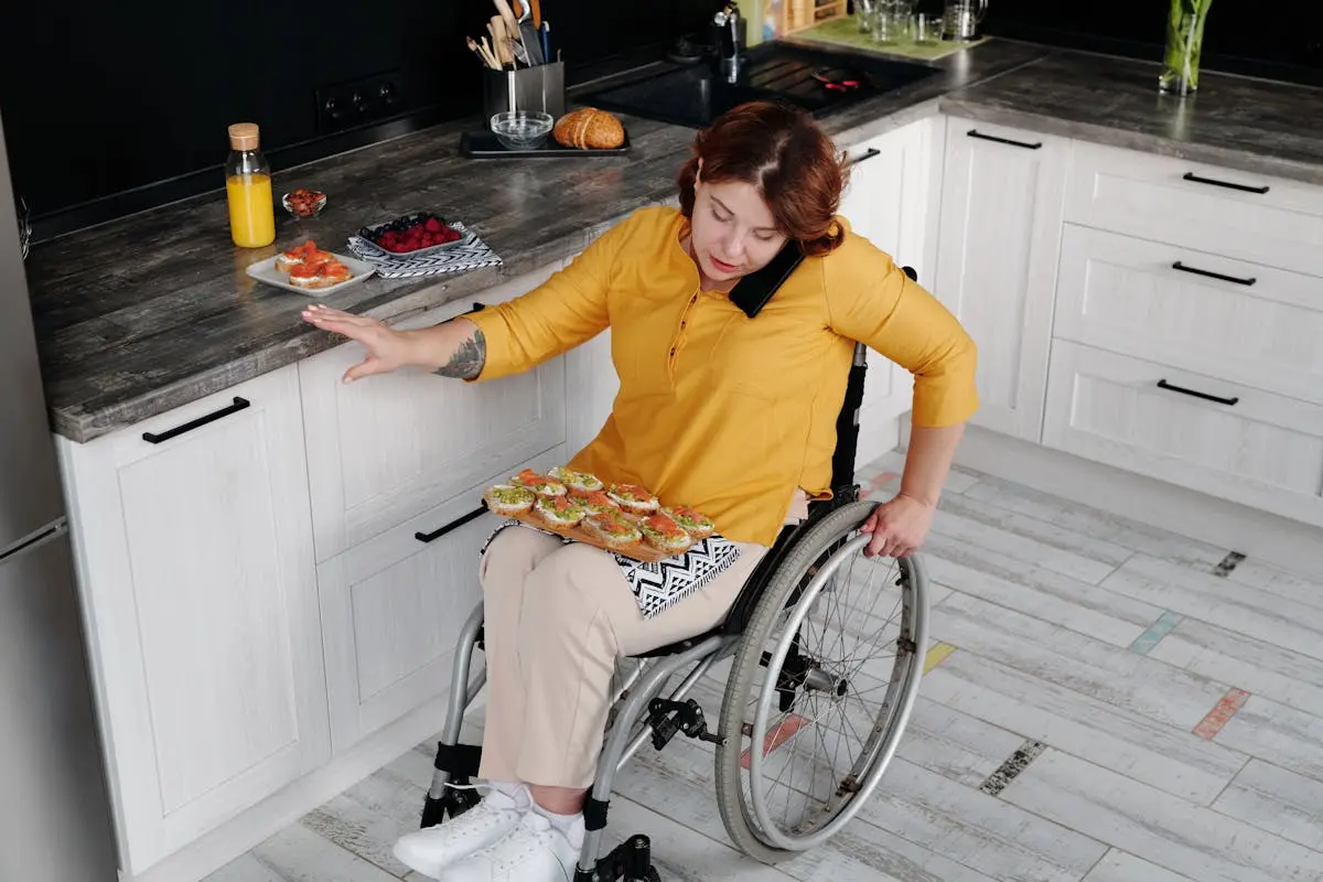 A woman in a wheelchair prepares food in a contemporary kitchen, showcasing everyday independence.