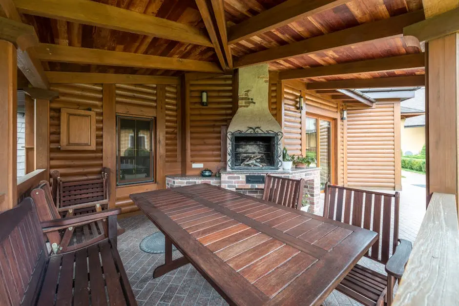 Wooden table and benches in terrace with fireplace under roof near building in daytime