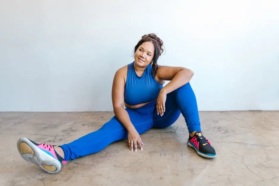 Confident plus-size woman in blue activewear sitting on the floor, embracing self-love and body positivity.