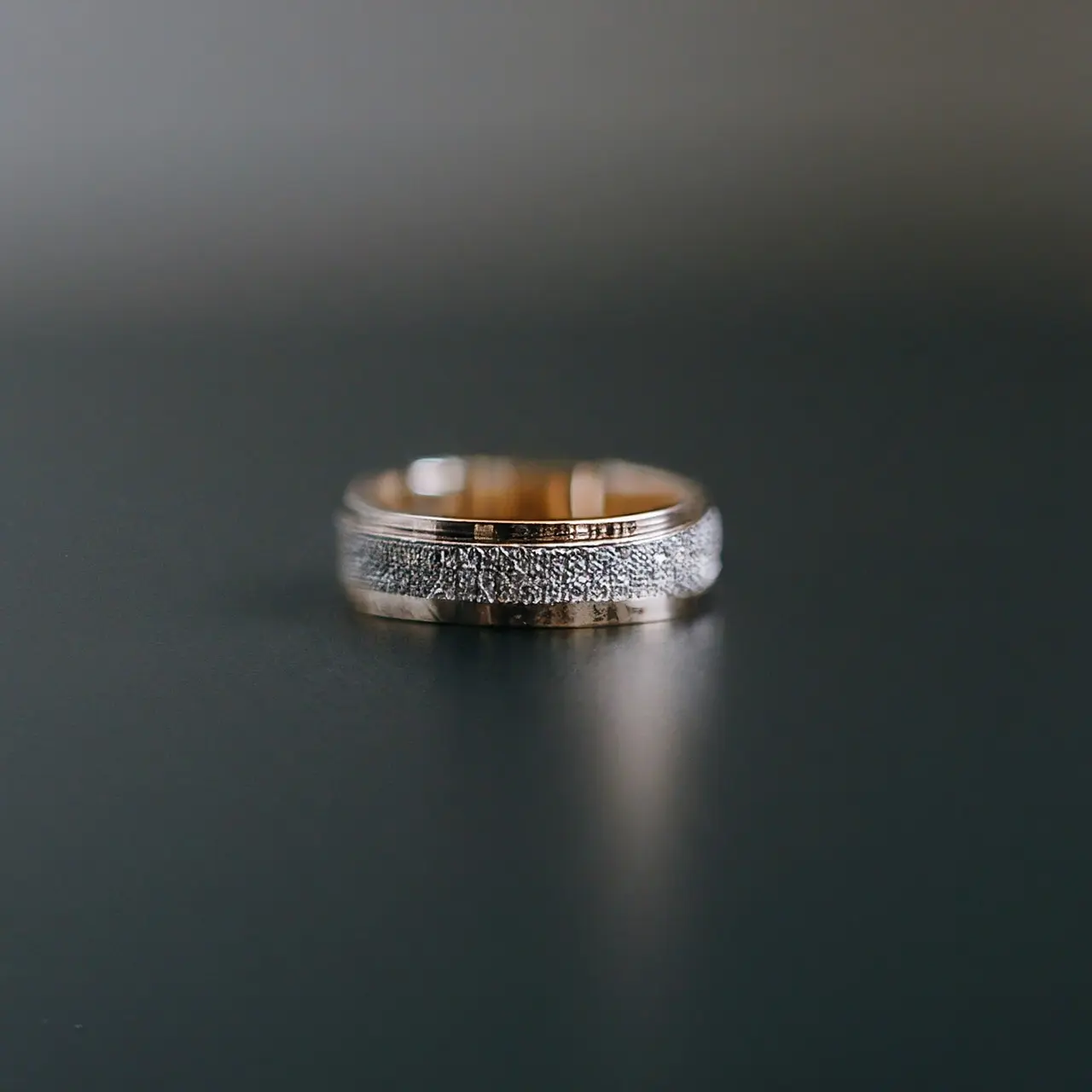 A luxurious gold wedding band on a sleek black background. 35mm stock photo