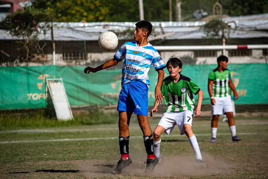 Teenagers engaging passionately in a competitive soccer match outdoors on a bright day.