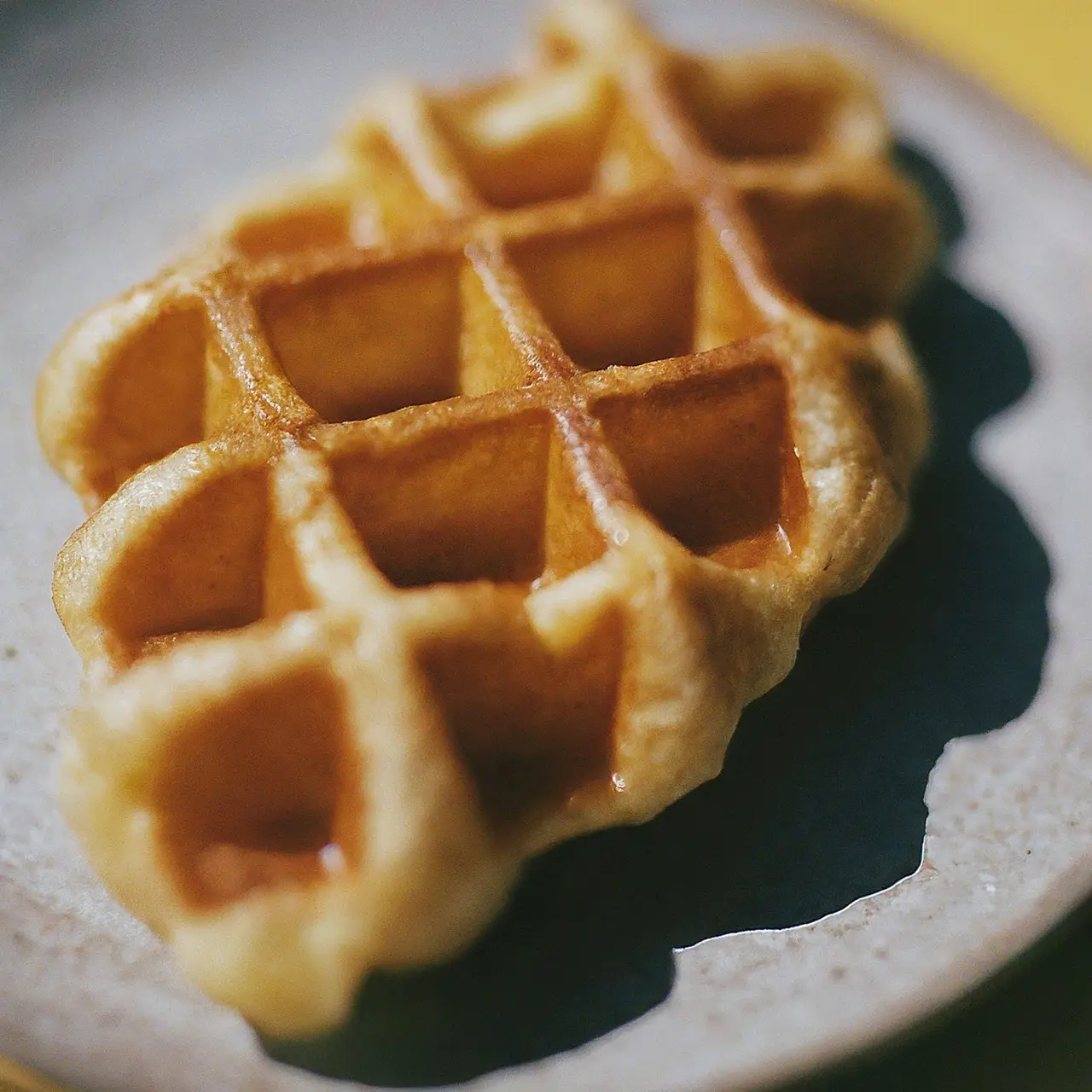 A close-up of a golden-brown cheese croffle on a plate. 35mm stock photo