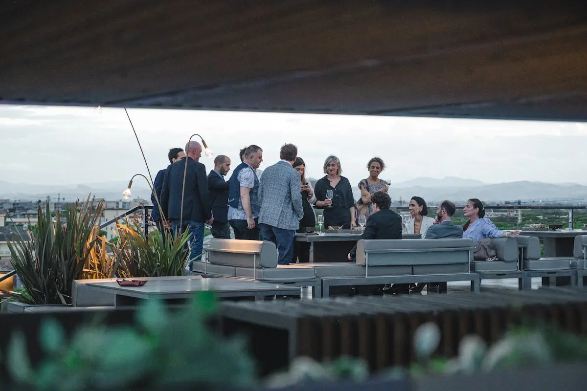 A group of adults enjoying a social gathering on a rooftop terrace with scenic views.