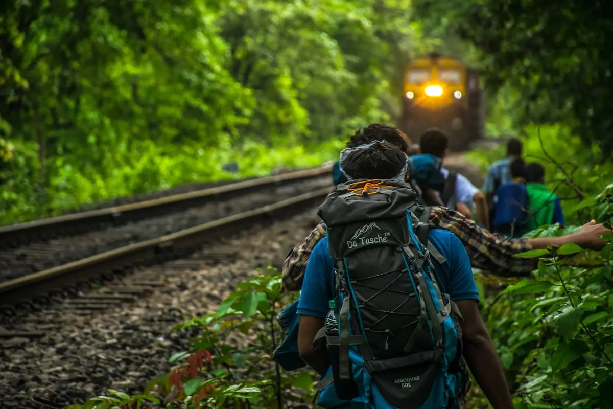 Group of People Walking Beside Train Rail wit their durable backpacks