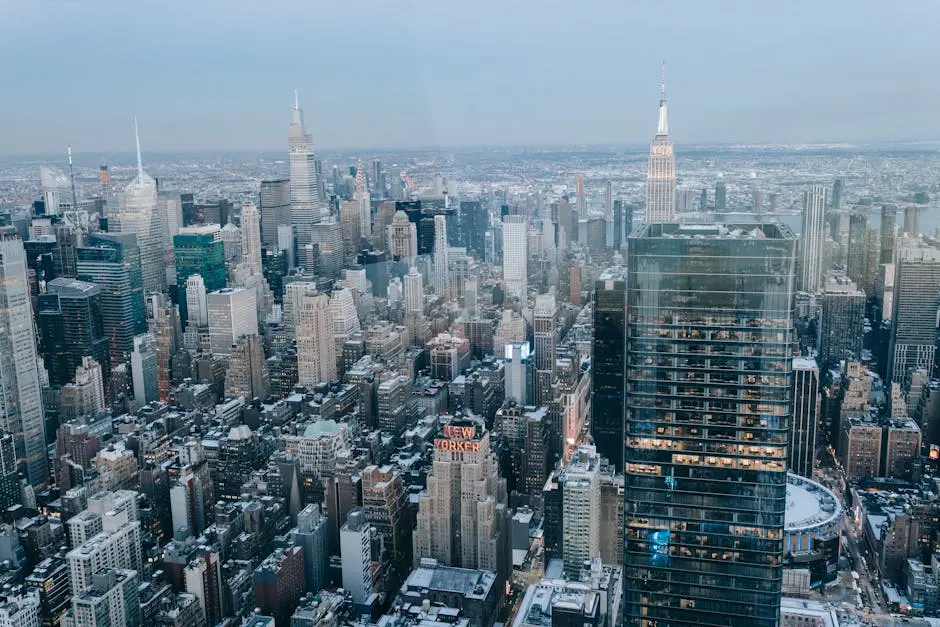 Drone view of modern high rise buildings and residential houses located on street of New York City against cloudless sky