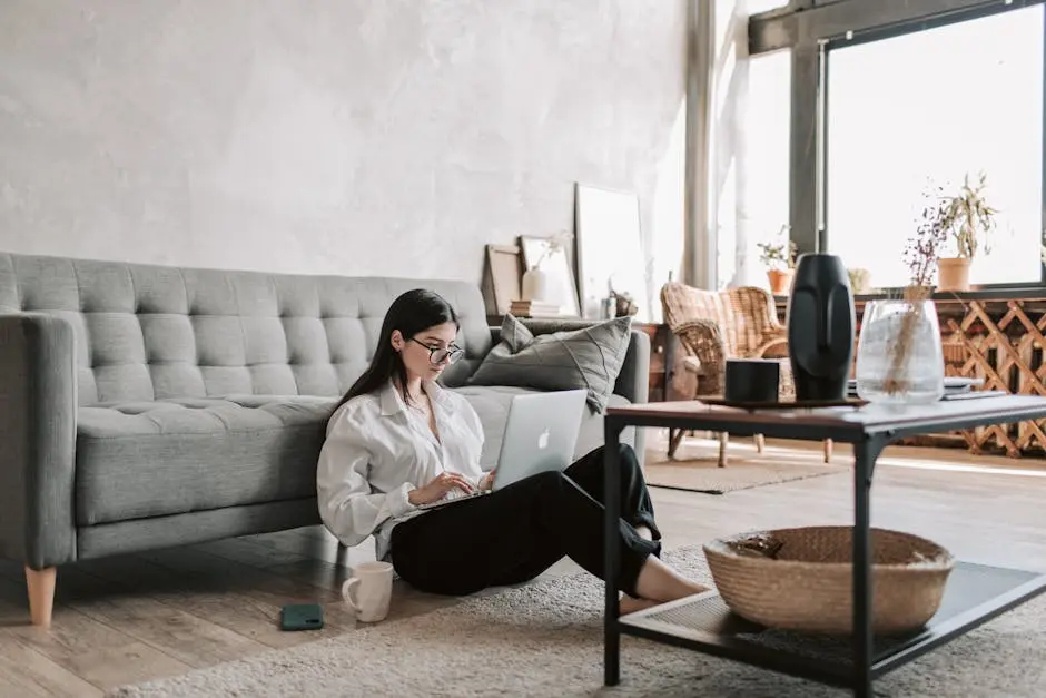 Una donna che lavora da remoto con un computer portatile in un appartamento elegante e ben illuminato, che incarna uno stile di vita moderno.