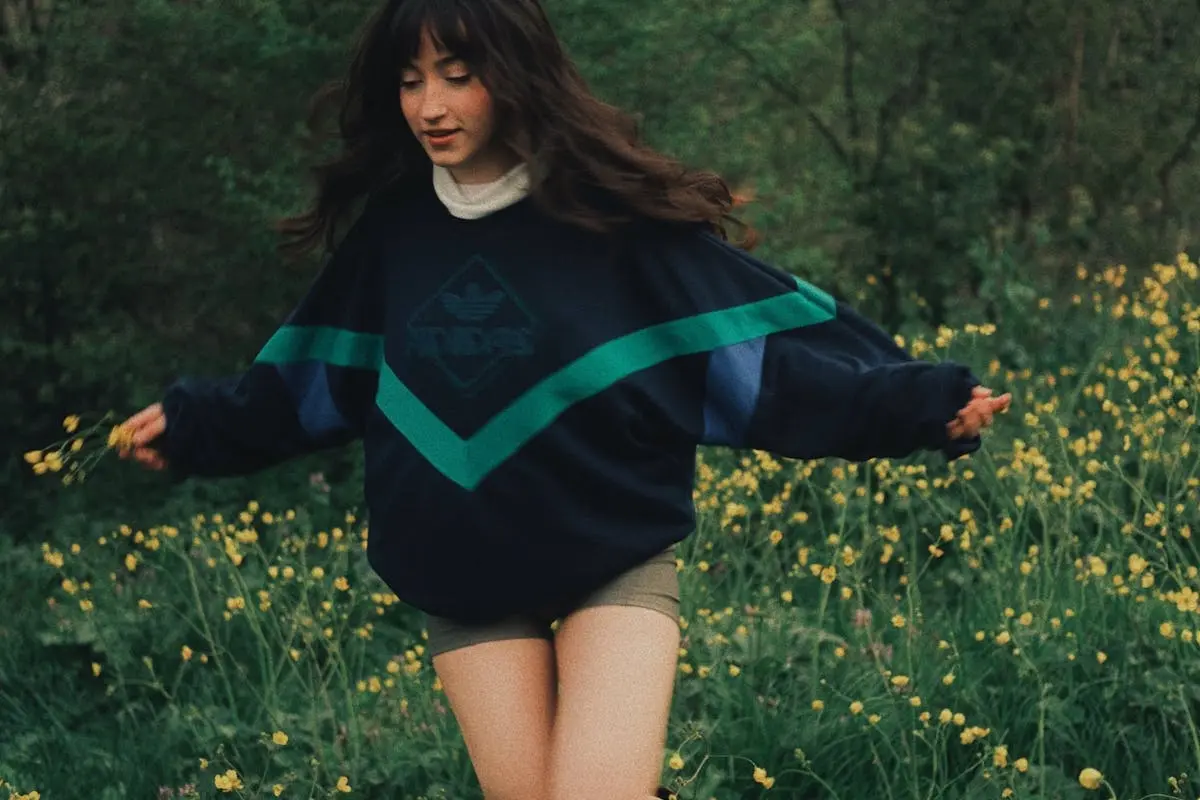 A woman in a sweater and boots is running through a field