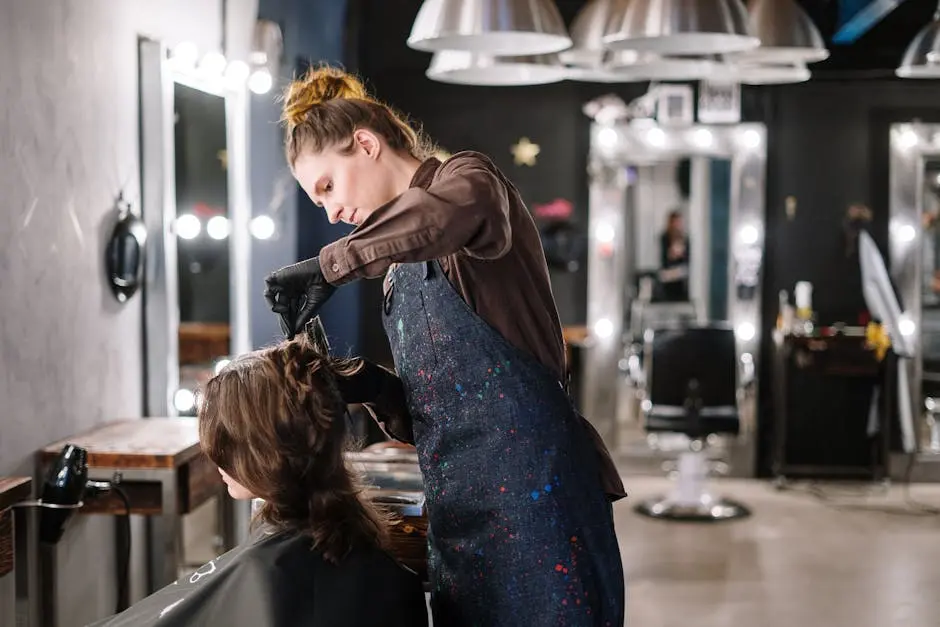 A female stylist expertly applying hair color to a client in a modern salon setting.