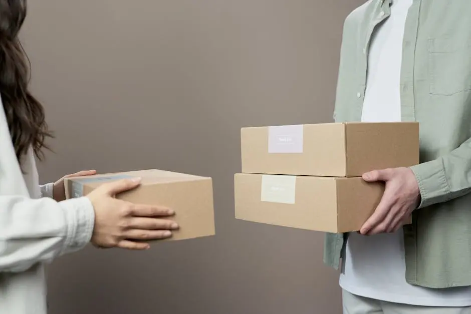 Two people exchanging cardboard boxes indoors, emphasizing teamwork and logistics.