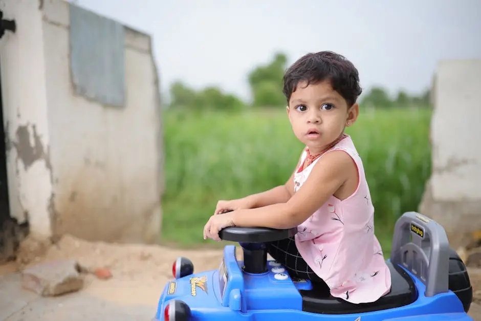 A little girl sitting in a blue toy car