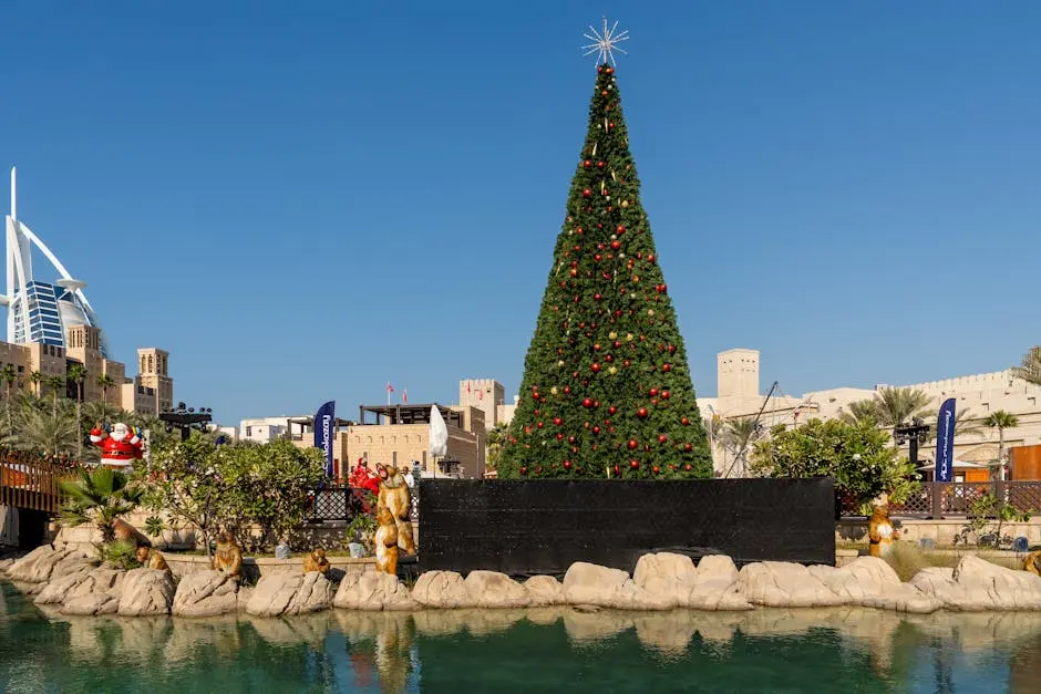 A festive Christmas tree stands tall against the backdrop of Burj Al Arab in Dubai, showcasing holiday spirit.