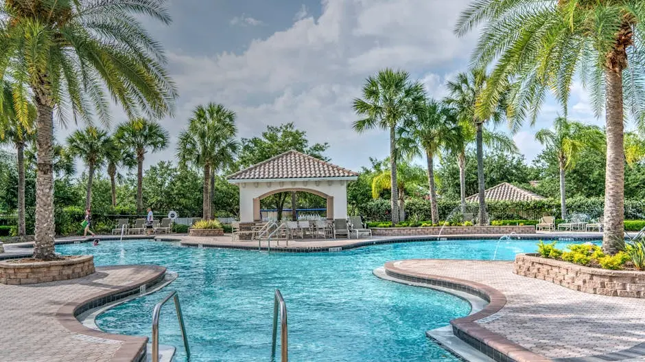 Relaxing tropical poolside scene with palm trees, gazebo, and clear blue water at a luxury resort.